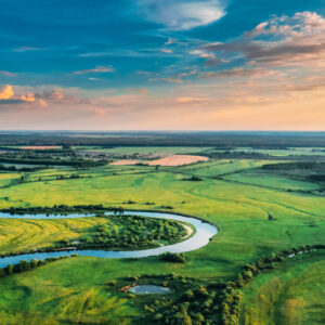 Aerial View. Sunny Sky Above Green Forest, Meadow And River Land